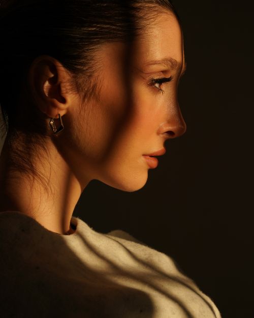 Free Close-up portrait of a woman in profile with dramatic shadows and warm lighting. Stock Photo