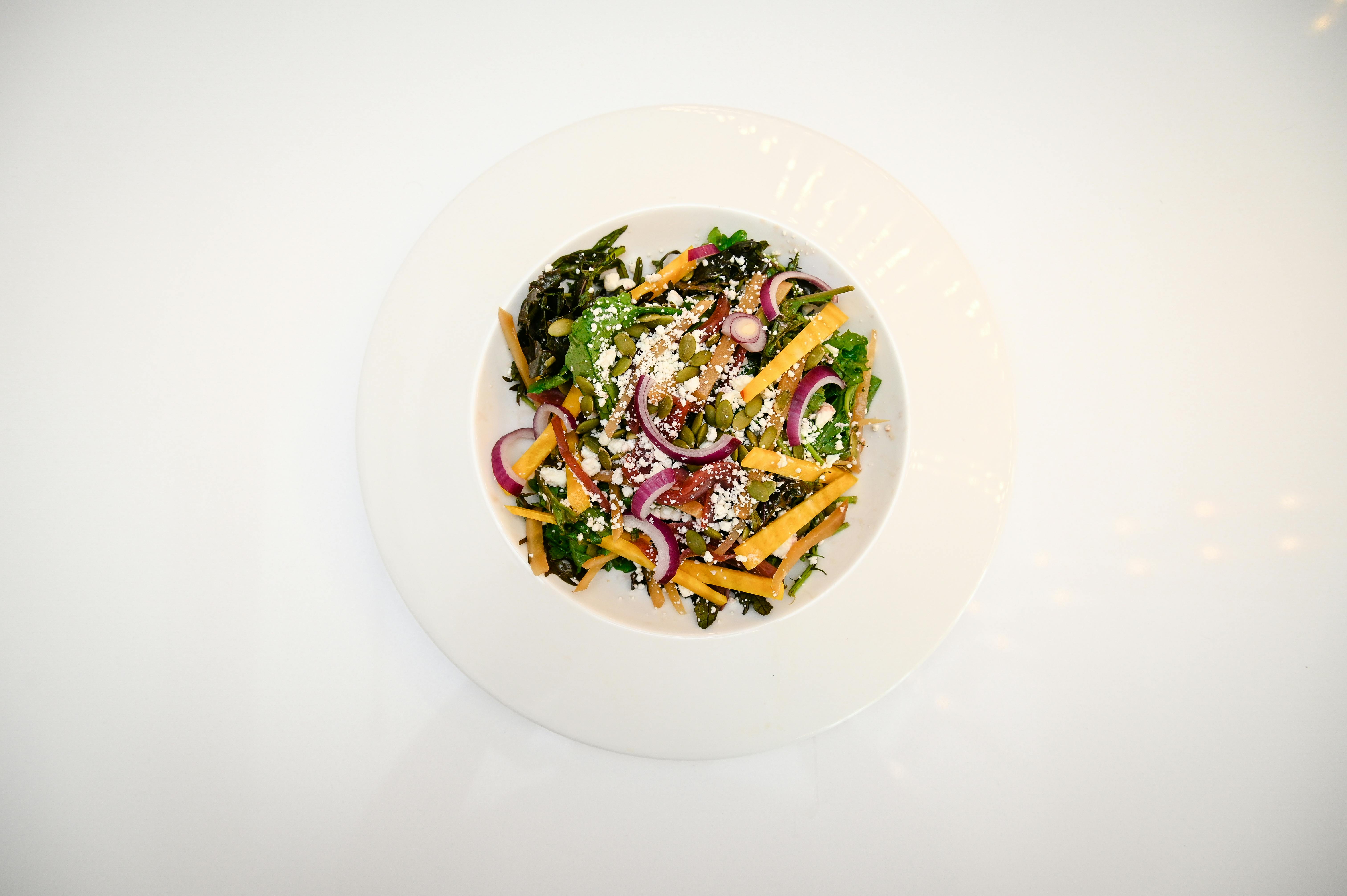 Top-down view of a colorful, nutritious vegetable salad with diverse toppings on a white plate.