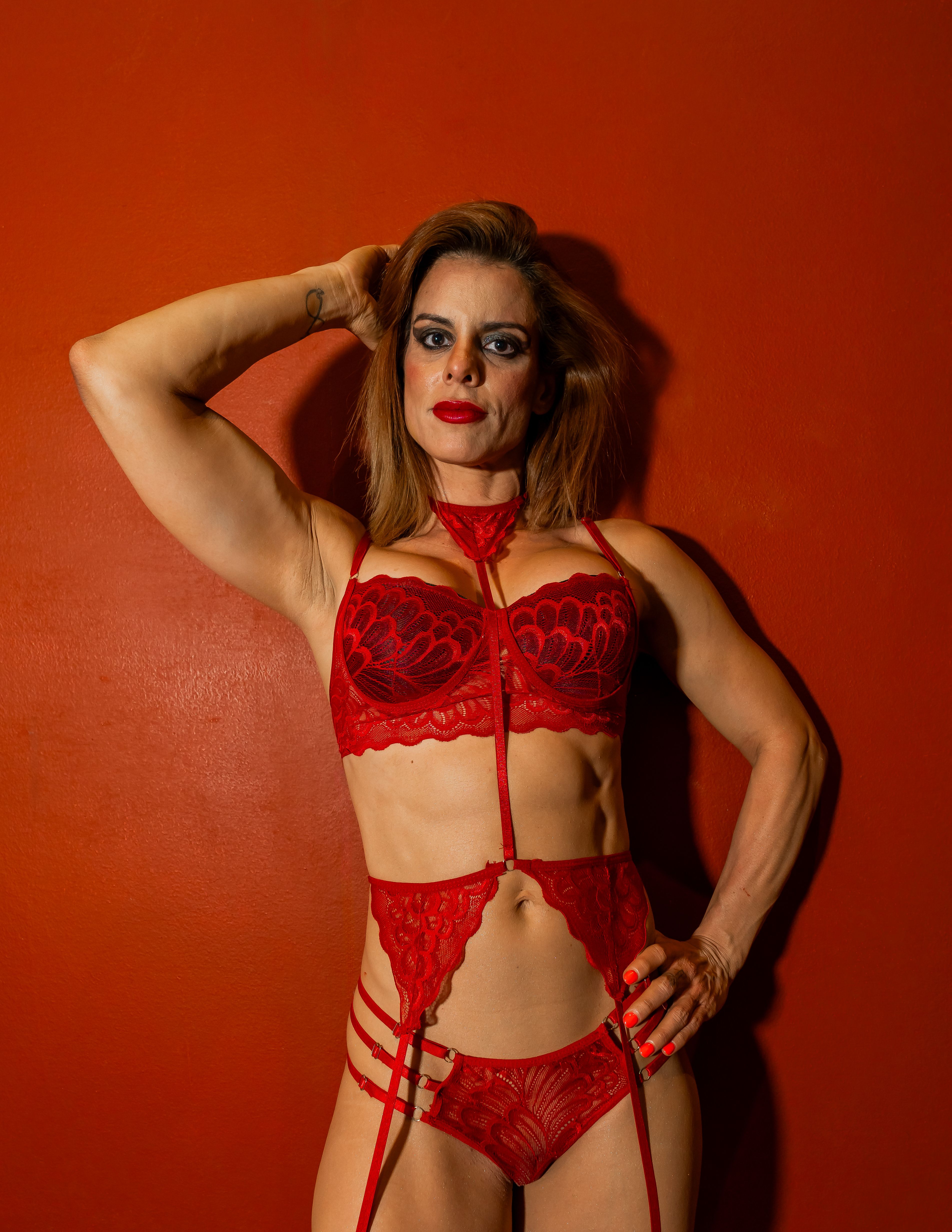 Intriguing surreal portrait of a woman in striking red lingerie with dramatic makeup.