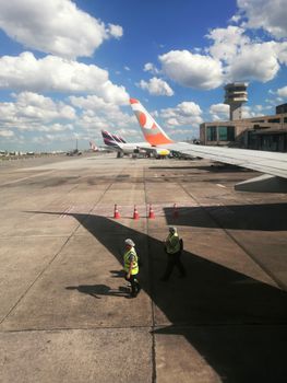 View from an airplane showcasing the wing, airport workers, and control tower at São Paulo Airport.