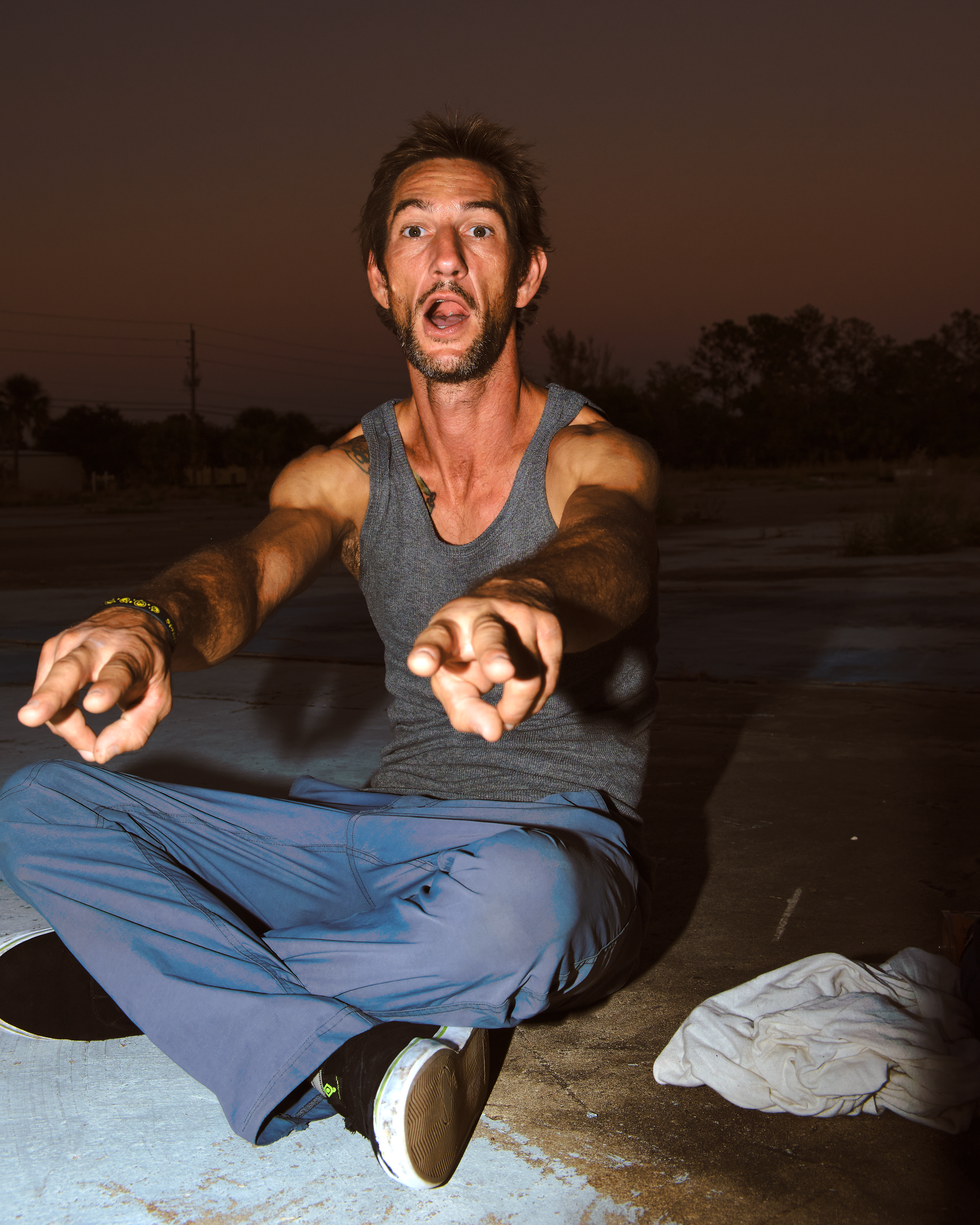 Adult man sitting and pointing dramatically in a twilight setting, evoking surprise.