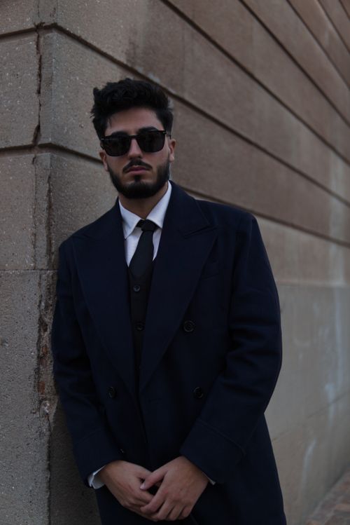 Free A bearded man poses confidently outdoors in a stylish outfit with sunglasses, exuding fashion-forward style. Stock Photo
