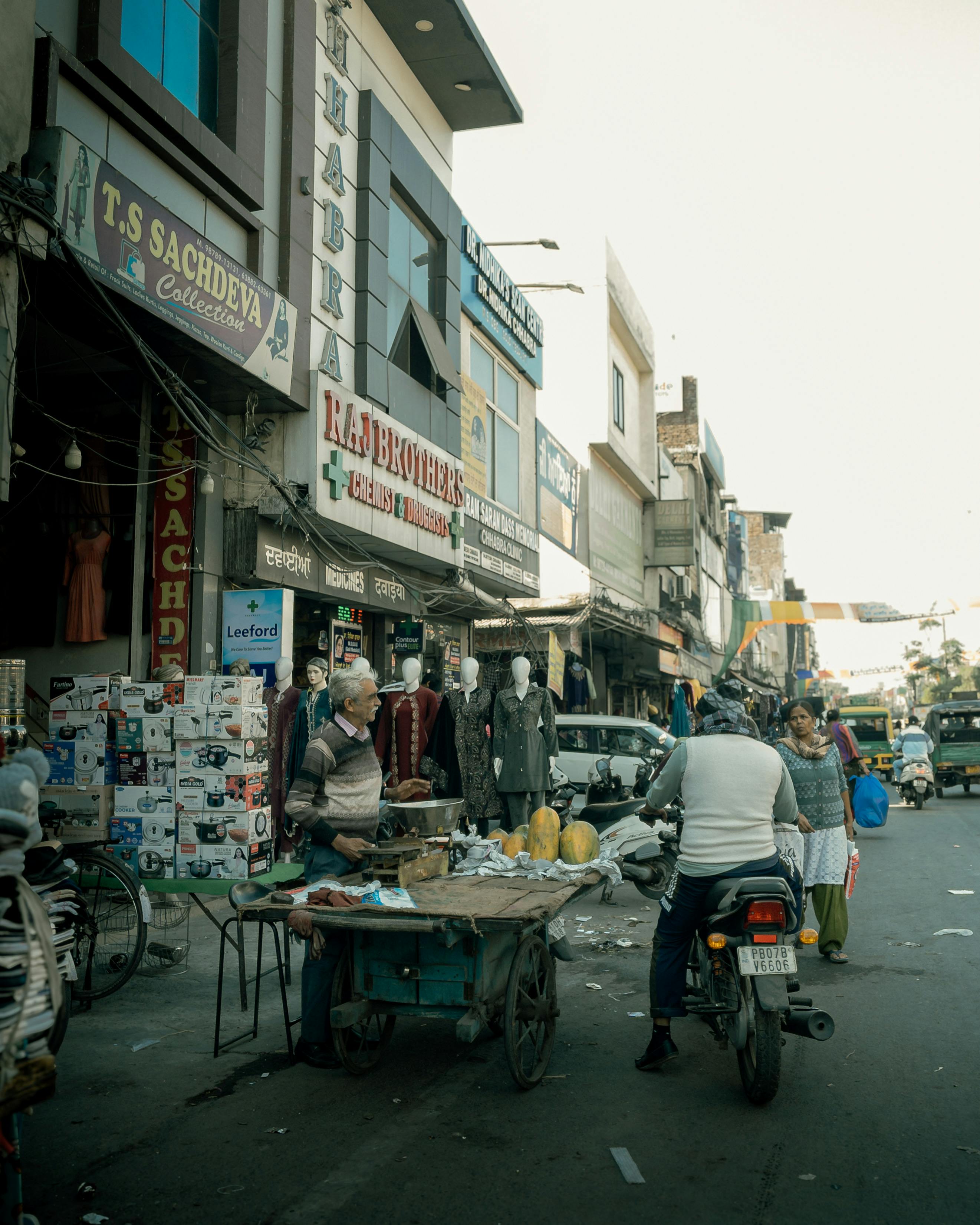 A vibrant street market scene in India with vendors and shoppers during the day.