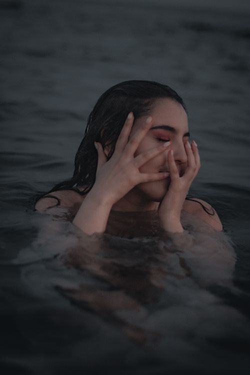 Free A woman in a calm body of water at twilight, evoking tranquility and introspection. Stock Photo