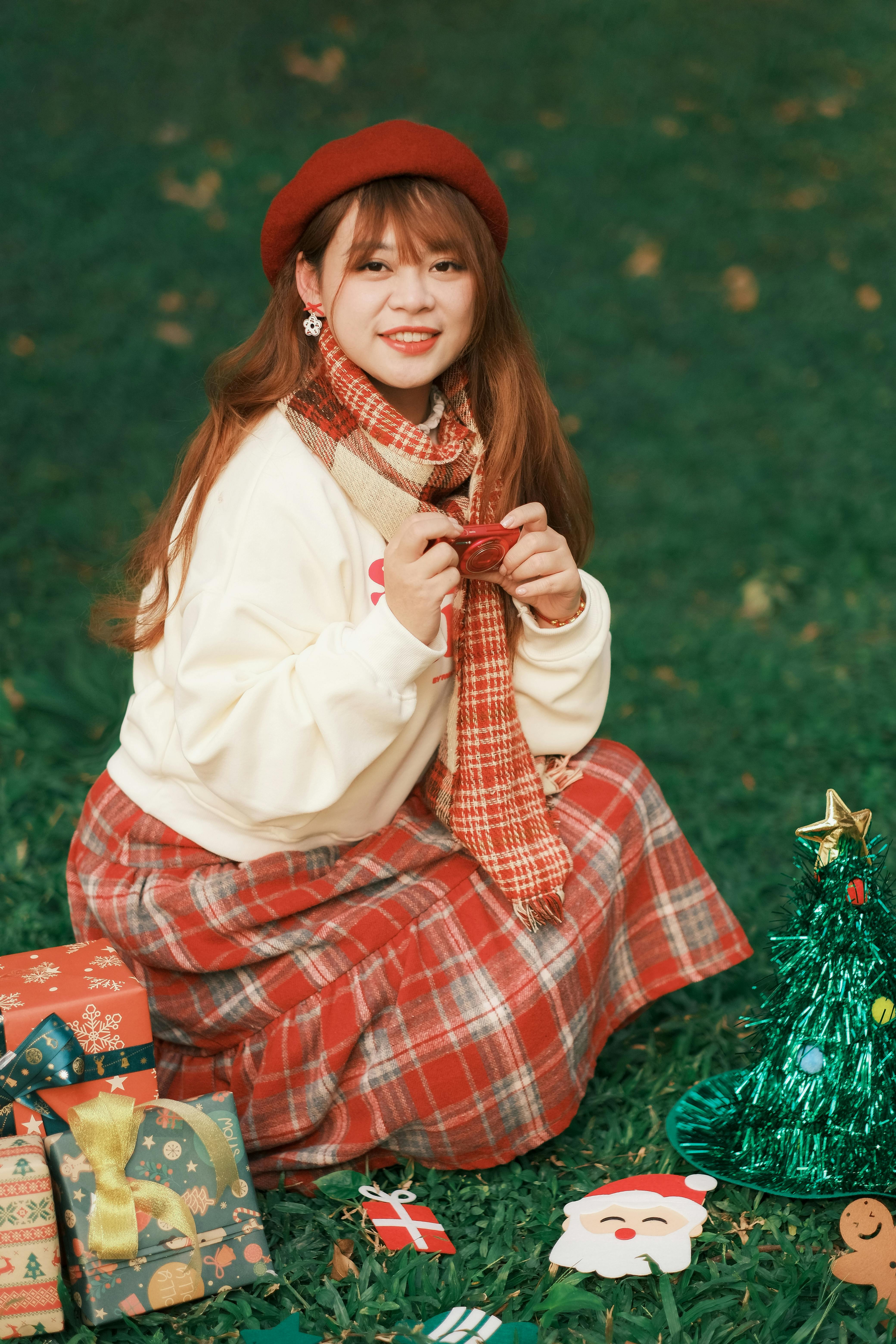 Young woman in winter attire with gifts and decorations in a park setting, embracing holiday cheer.