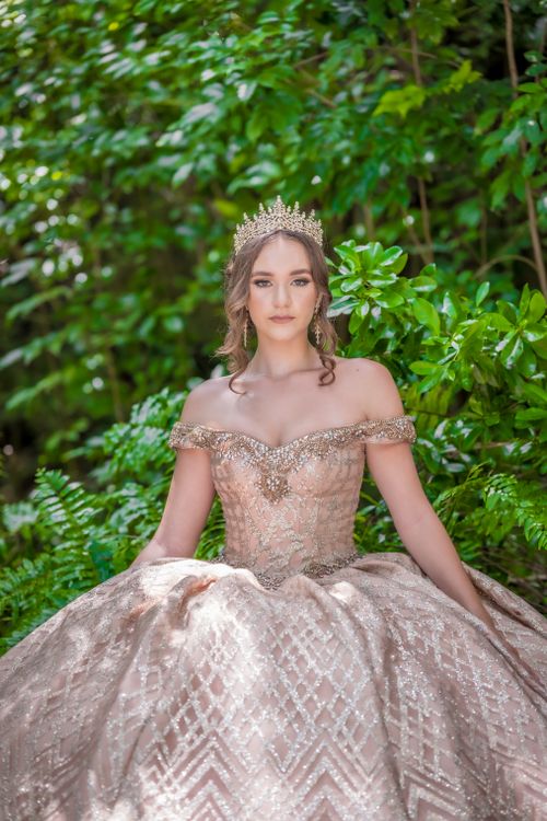 Free Beautiful woman in an ornate gown with crown, surrounded by lush greenery, exuding a regal presence. Stock Photo