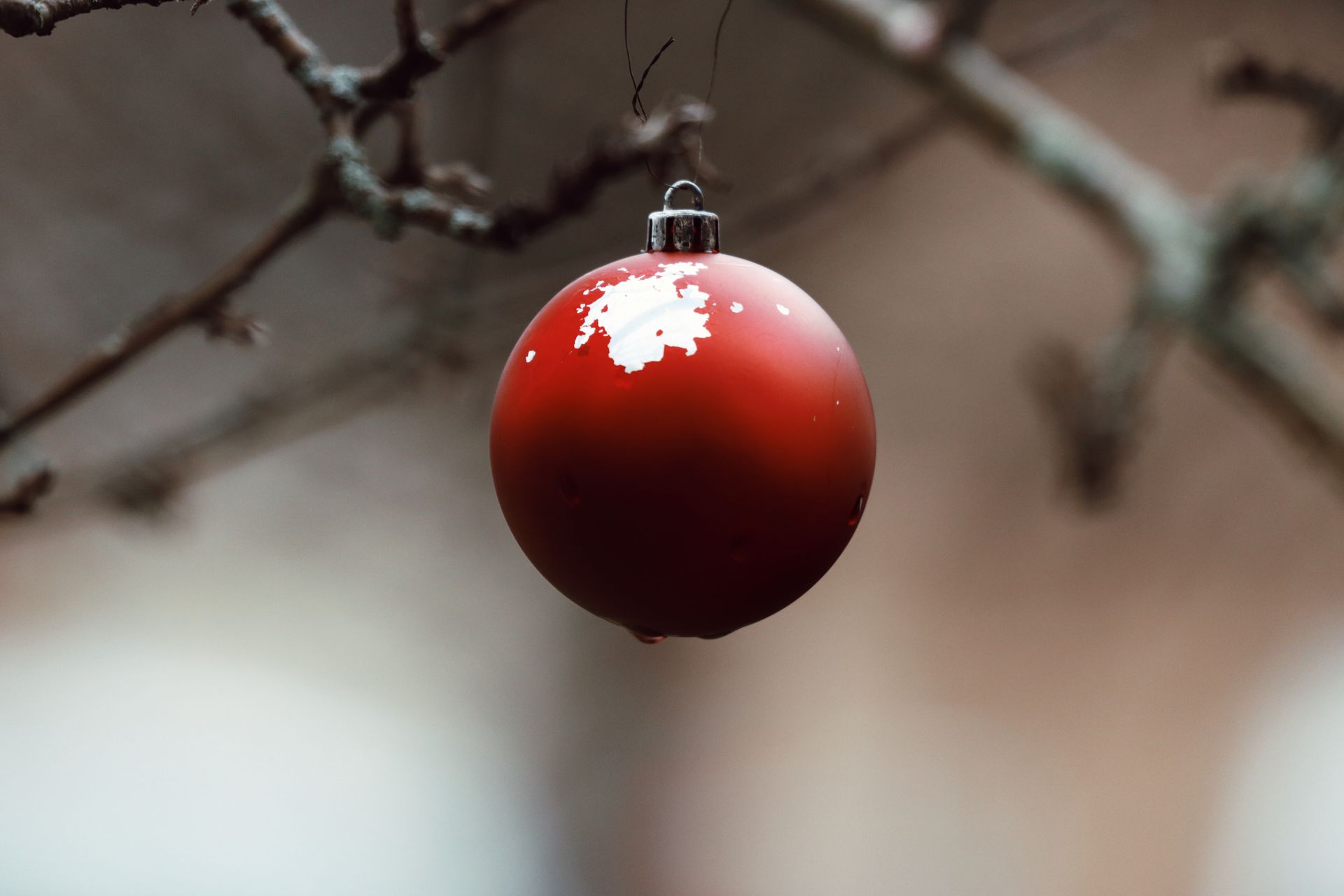 A red Christmas ornament hanging on a bare tree branch in winter in Jönköping, Sweden.