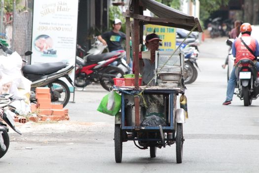 A street food vendor selling snacks on a busy road, surrounded by motorbikes.