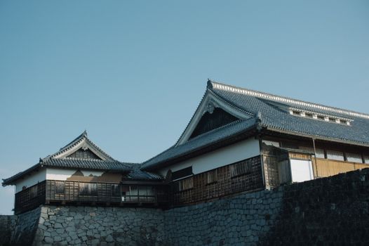 Explore the rich history and architecture of a traditional Japanese castle under a clear blue sky.