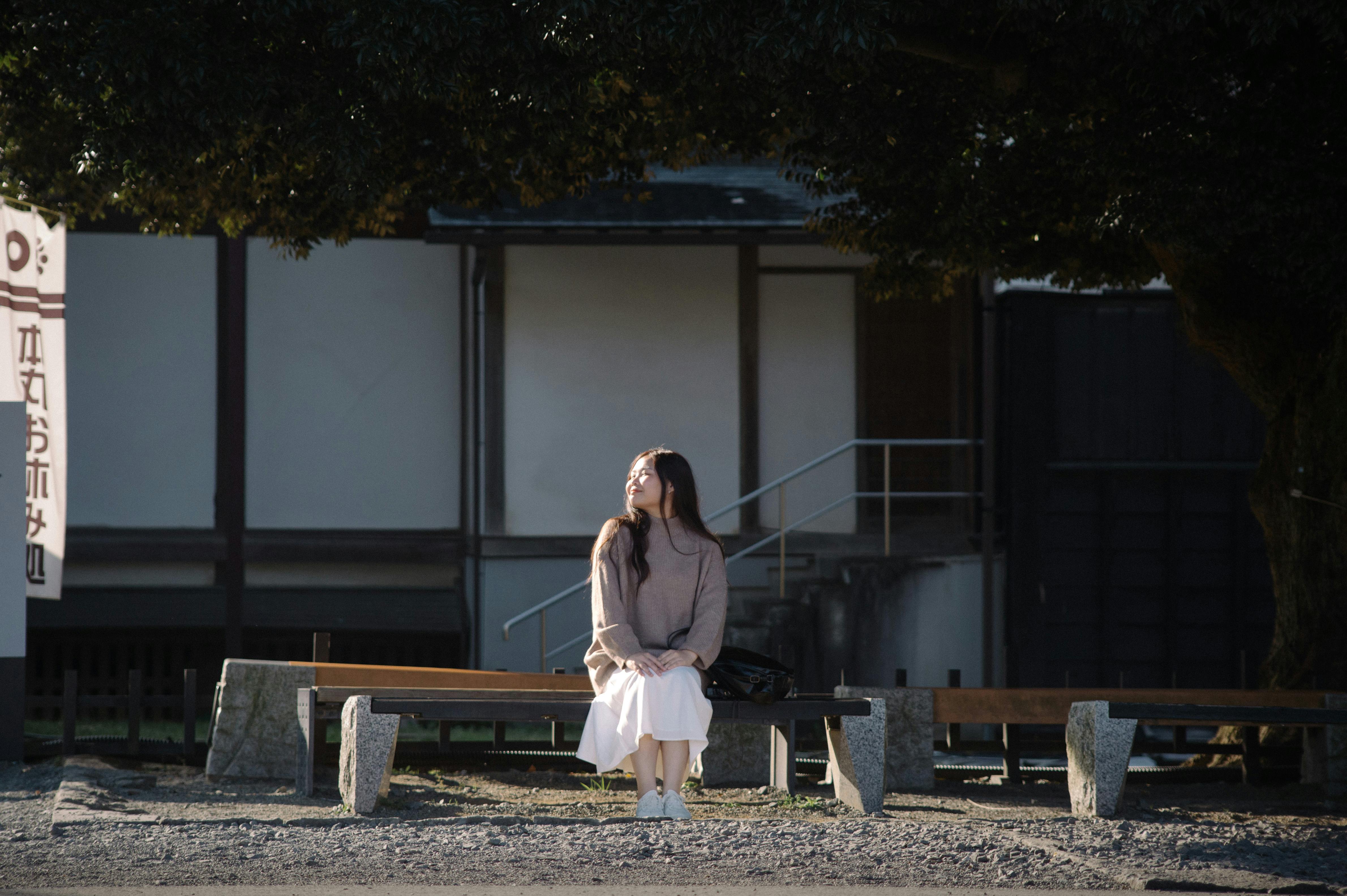 Une jeune femme profitant d'une journée ensoleillée sur un banc sous un arbre au Japon.