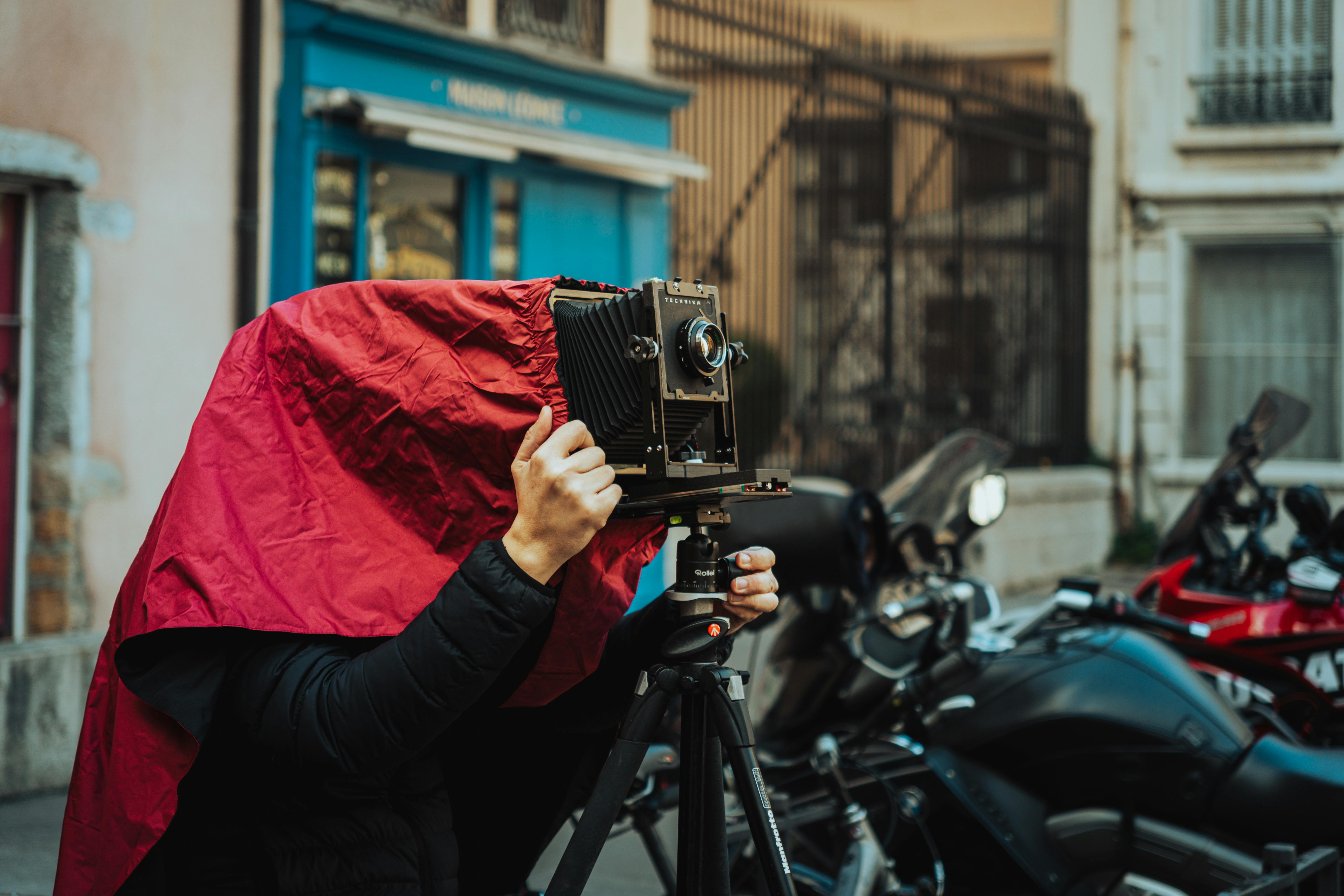 Photographer using a large format camera on a busy street, showcasing vintage photography techniques.