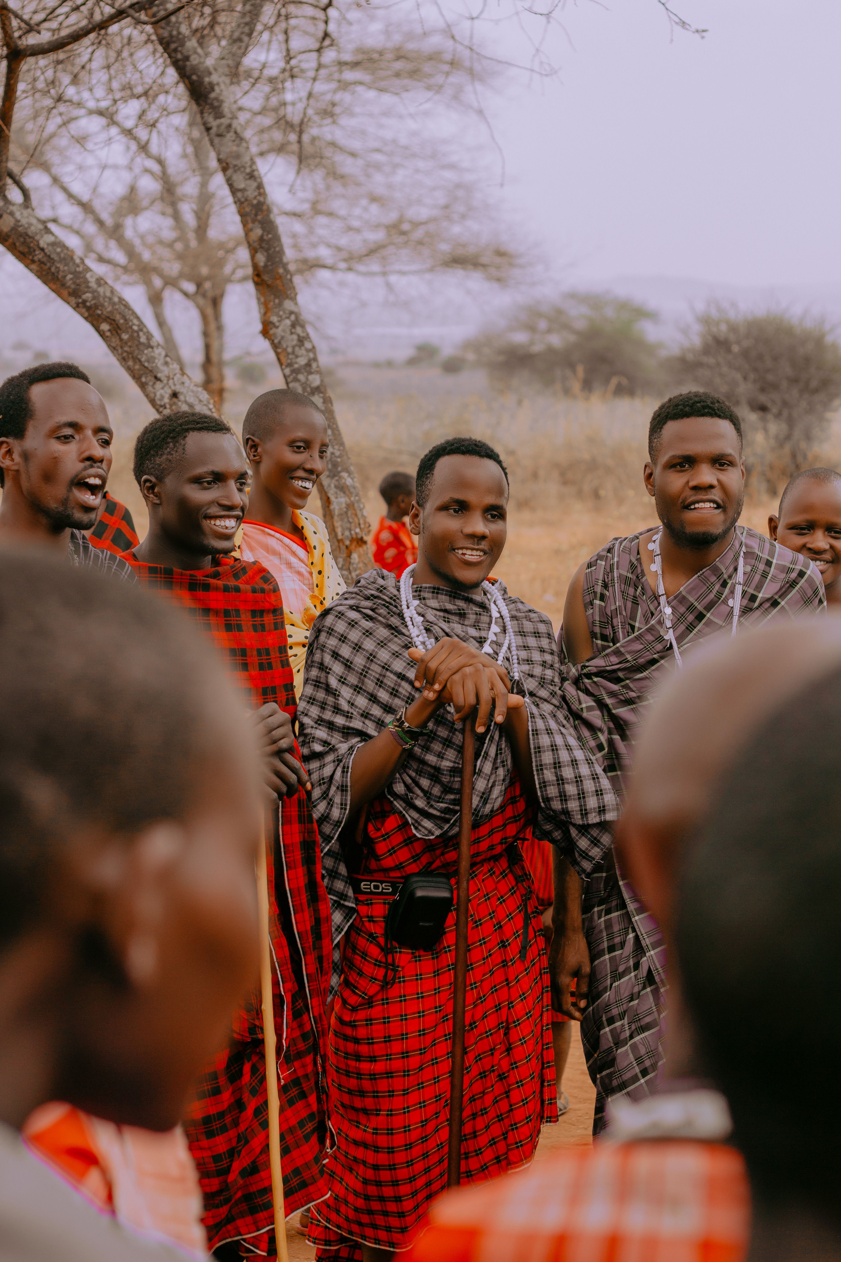 A group of Maasai men wearing traditional clothes in an outdoor setting.