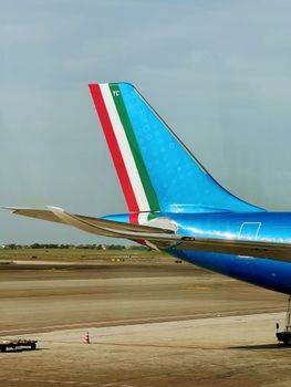 Close-up view of airplane tail featuring Italian flag colors on a runway in Lazio, Italy.