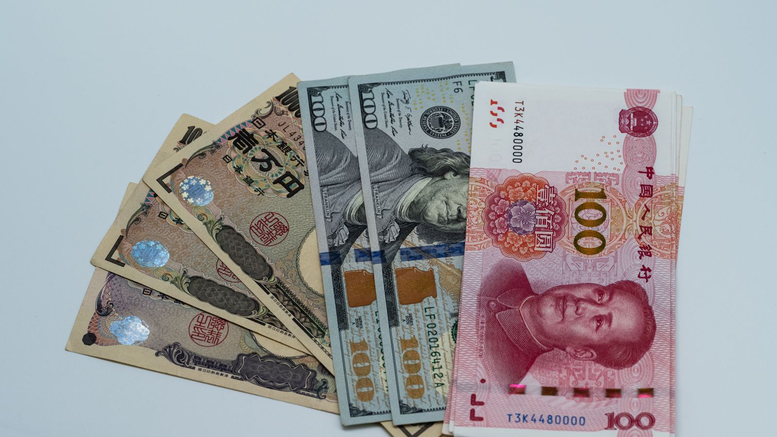 円やドルなど国際通貨の紙幣が並べられ、為替相場の動向を示すイメージ
