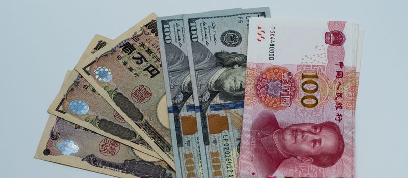 円やドルなど国際通貨の紙幣が並べられ、為替相場の動向を示すイメージ