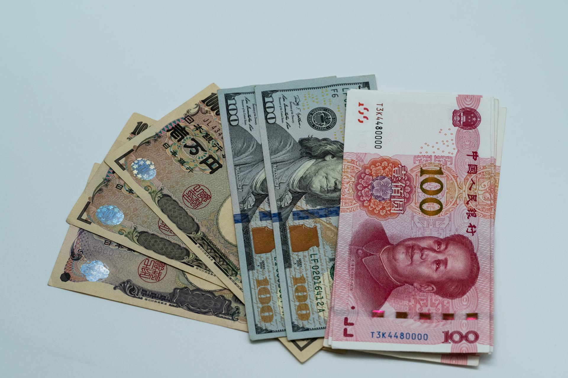 Various international currency notes including US dollars, yen, and yuan arranged on a surface.