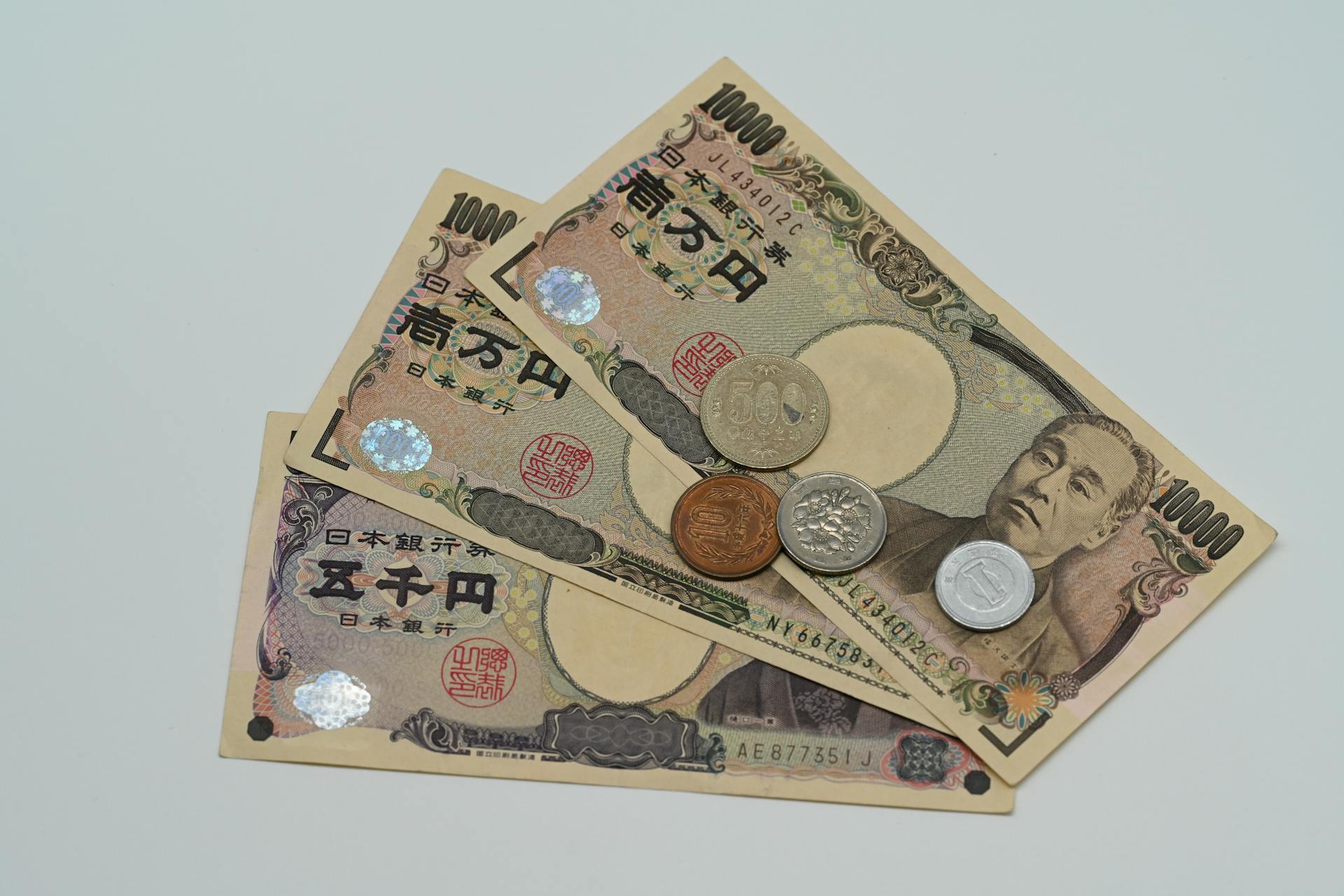 Close-up of Japanese Yen banknotes and coins arranged on a flat surface.