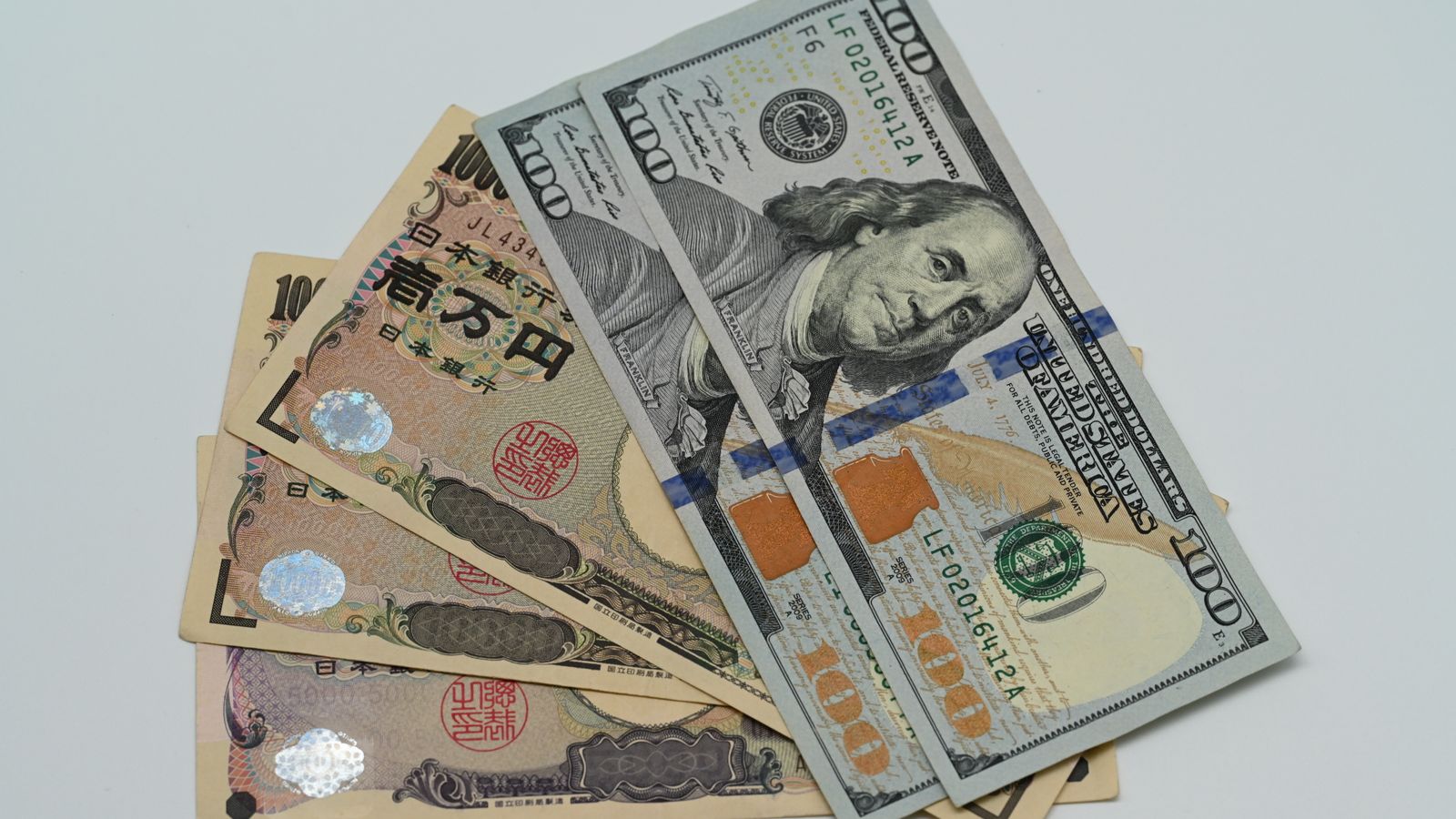 米ドルと日本円の紙幣が並び、円を基軸とする世界金融の不安定さを連想させるイメージ