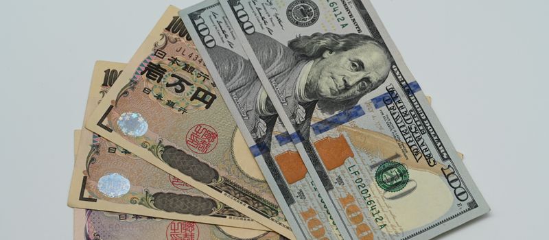 米ドルと日本円の紙幣が並ぶクローズアップ。日銀の利上げと為替相場の動向を示すイメージ。