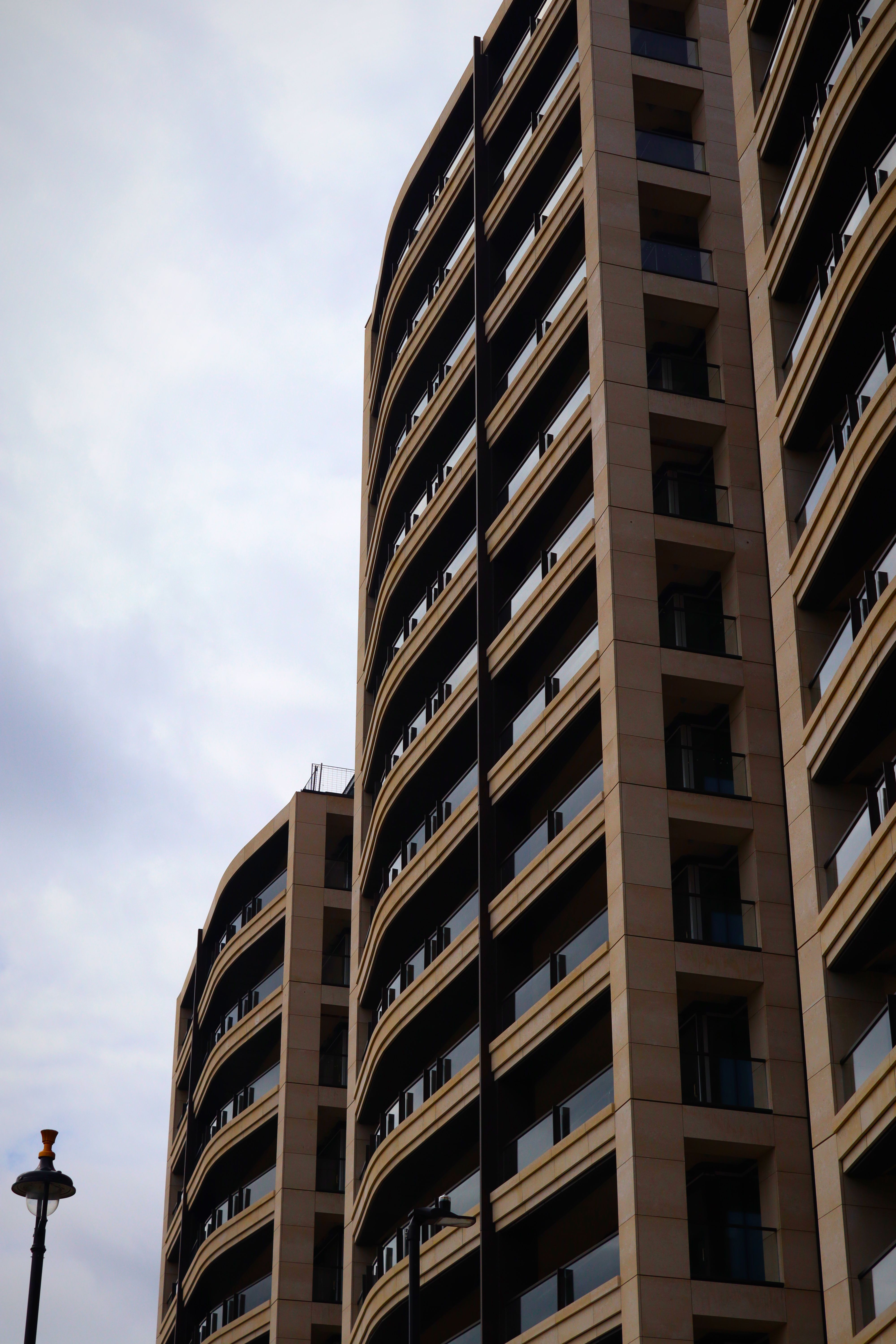 Modern brick residential tower with balconies, overcast sky