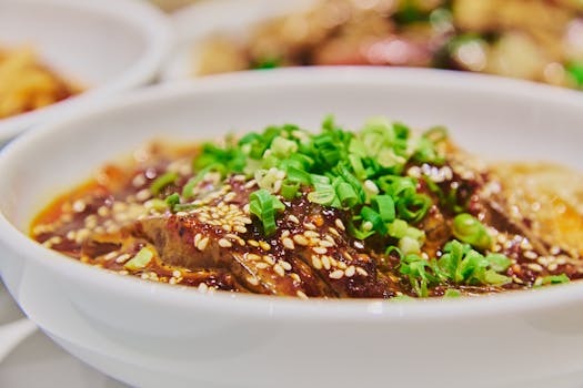 Close-up of a savory Asian dish garnished with scallions and sesame seeds.