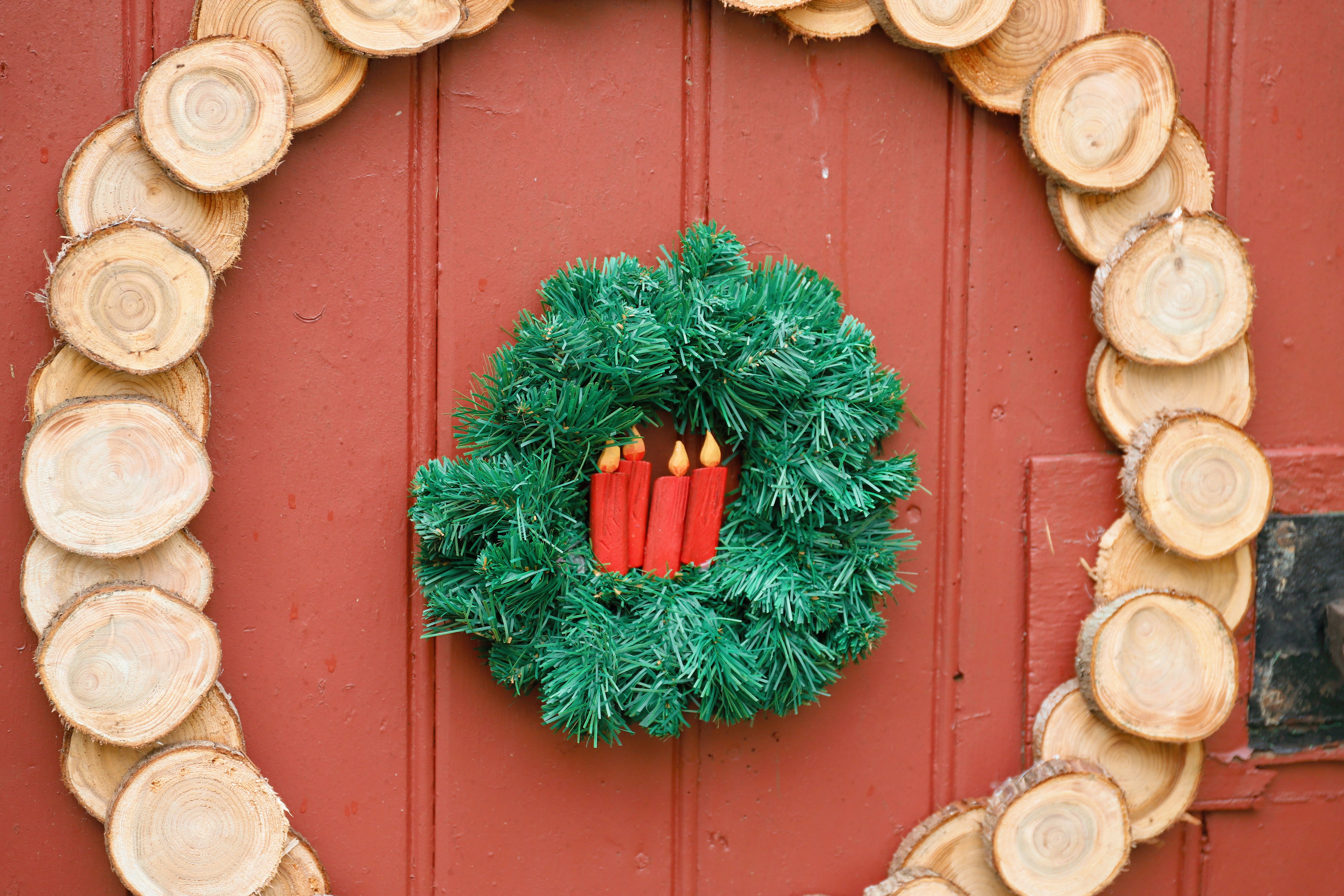Festive Christmas wreath with red candles on a wooden door, evoking holiday spirit.