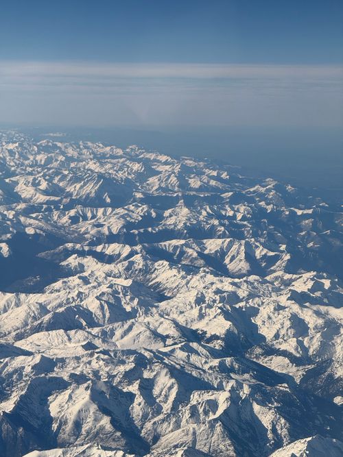 Free A breathtaking aerial view of a snow-covered mountain range on a clear day. Stock Photo