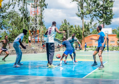 Diverse group of people playing basketball outdoors on a sunny day, showcasing teamwork and energy.