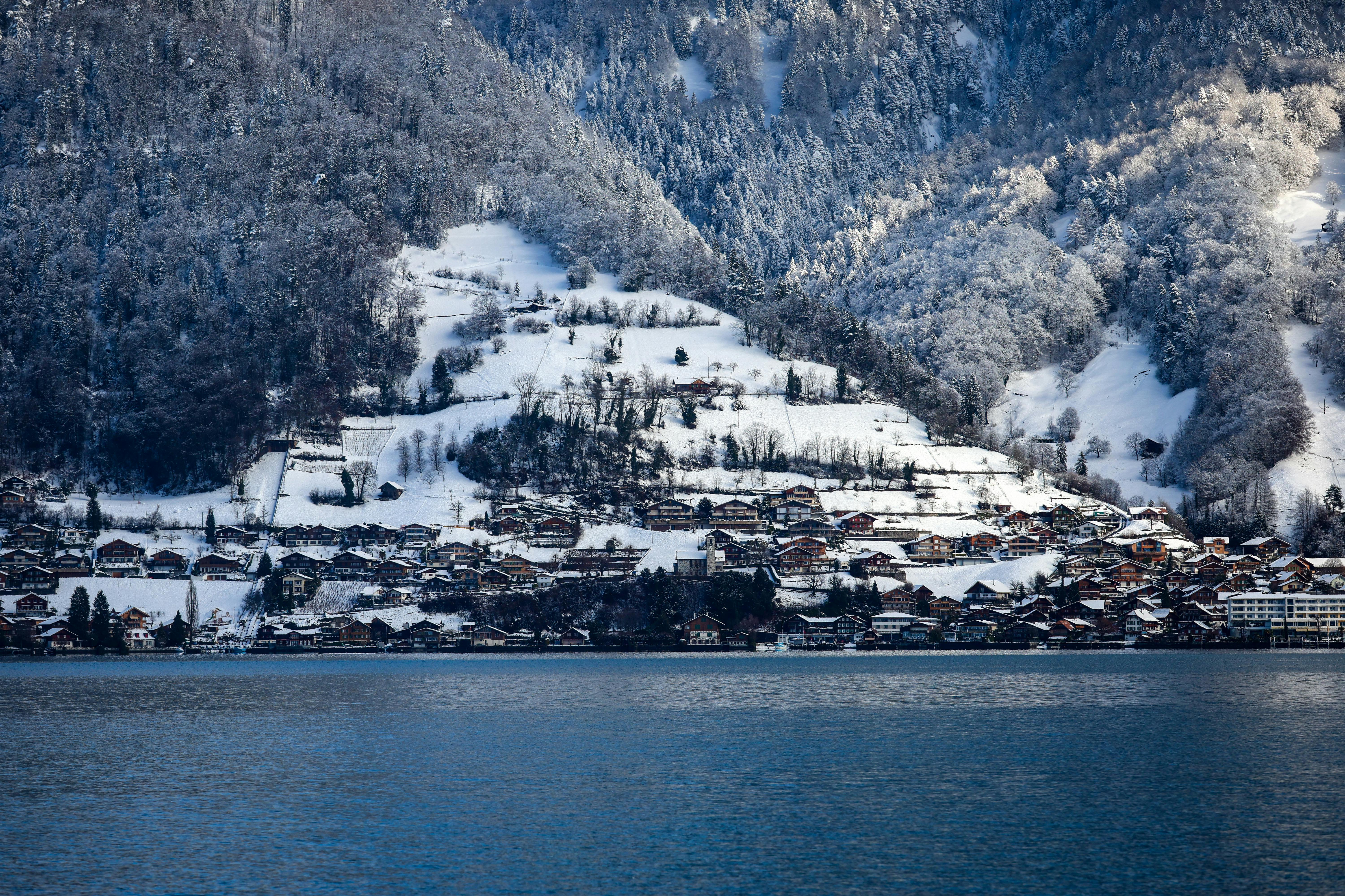Peaceful snowy Swiss village nestled by a serene lake with scenic mountain backdrop.