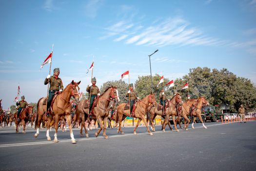 Mounted guards in ceremonial attire parade through New Delhi, India under a clear blue sky.