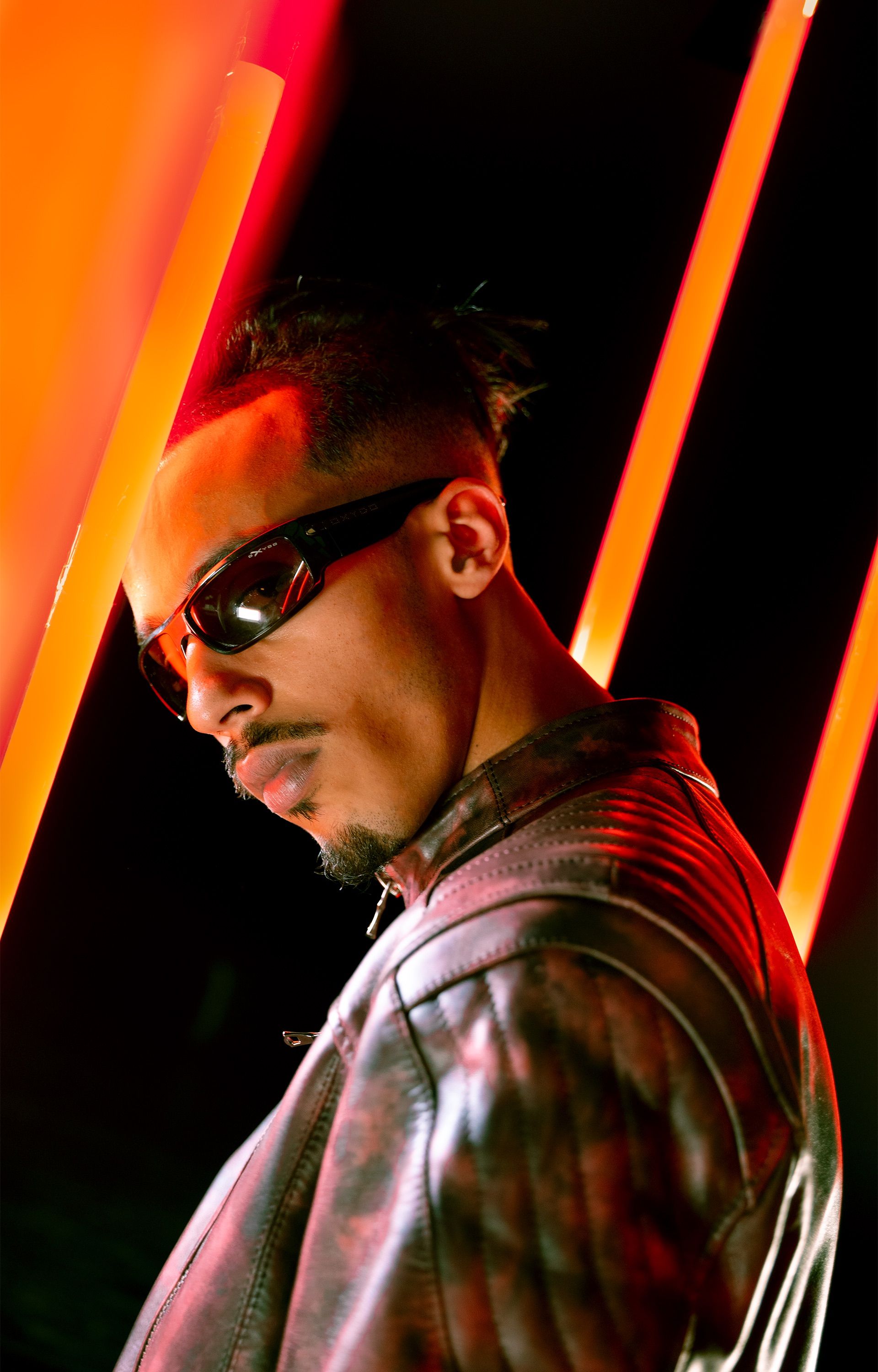 Stylish young man in leather jacket and sunglasses with red neon lights.