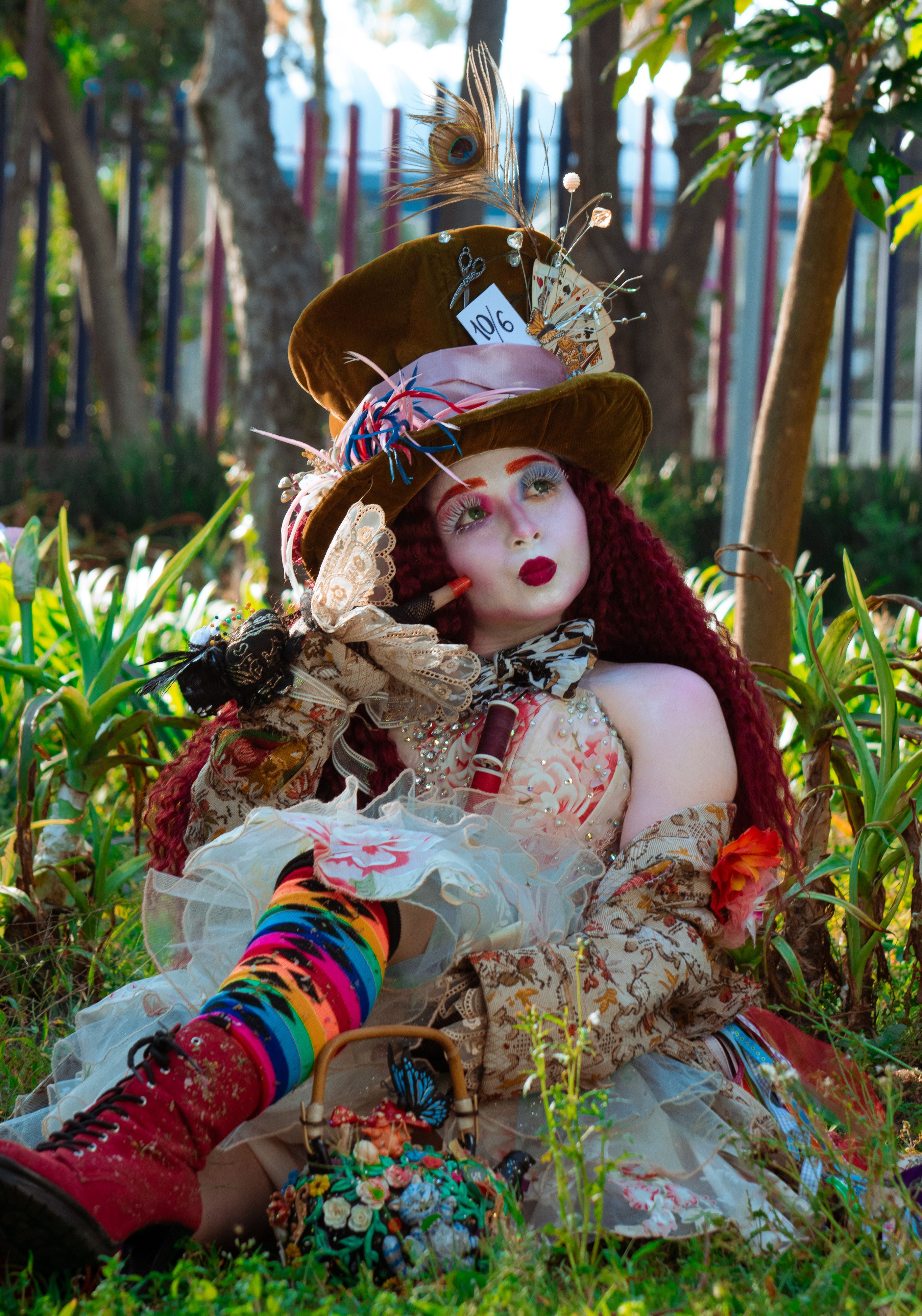 Vibrant Mad Hatter cosplay with intricate costume and accessories set in a lush garden.