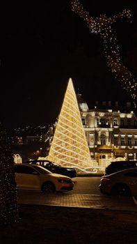 Illuminated Christmas tree in Baku with festive lights and cityscape at night.