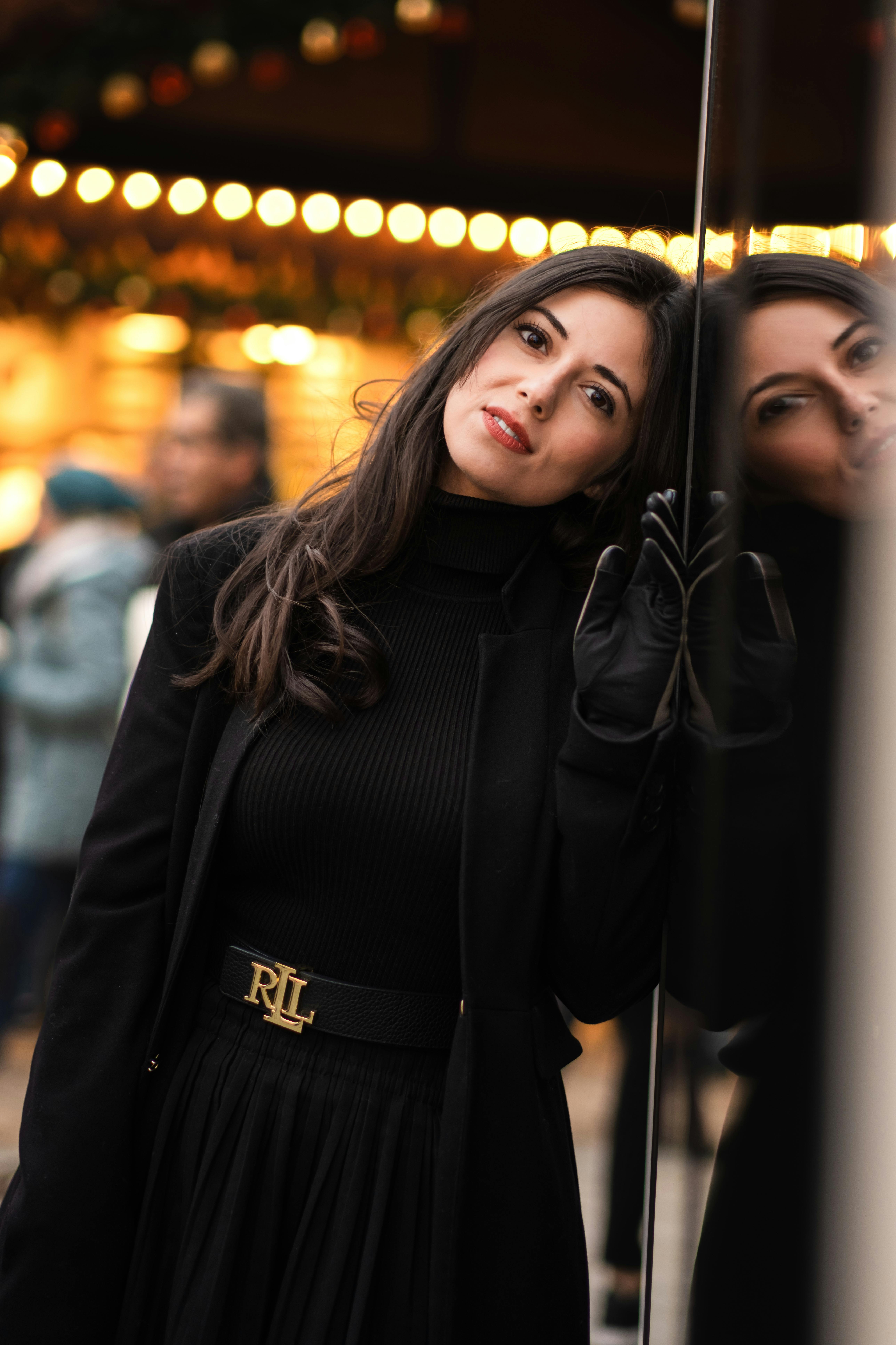 bezplatná Žena v černém opřená o reflexní plochu na pulzujícím vánočním trhu v německém Düsseldorfu. Základová fotografie