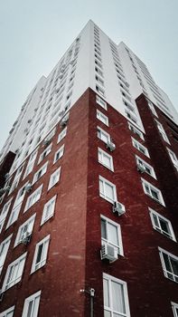 Upward view of a tall brick residential building during a snowy winter day.