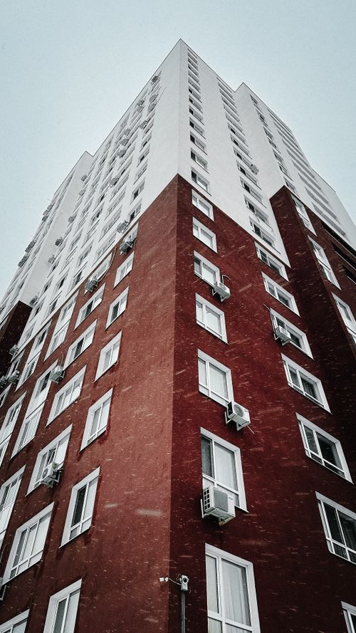 Free Upward view of a tall brick residential building during a snowy winter day. Stock Photo