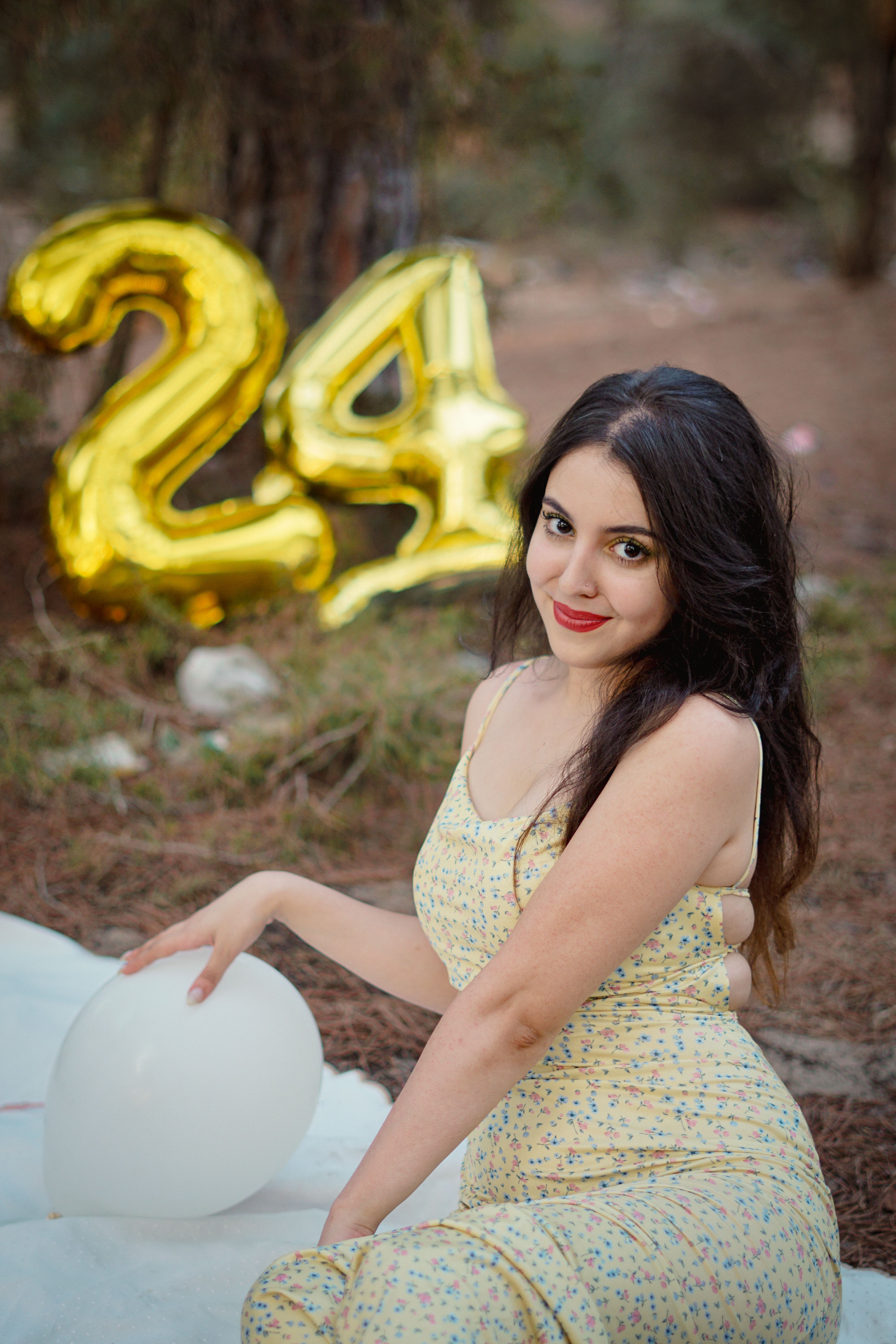 Enjoy a captivating outdoor birthday scene with a young woman and festive balloons.