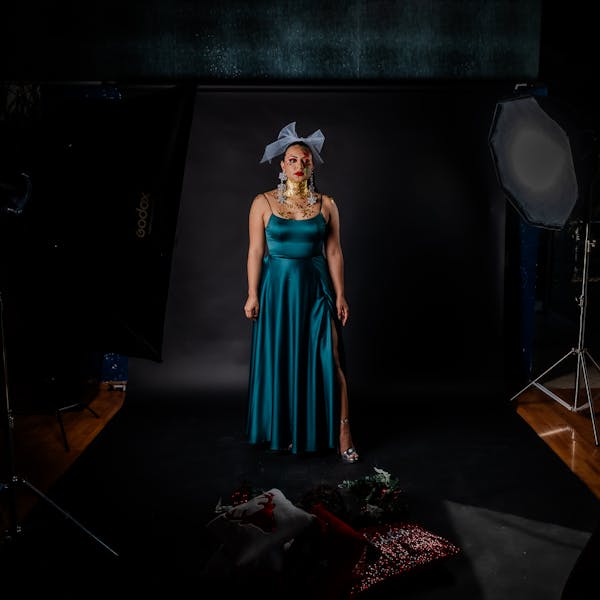 Artistic portrait, teal dress, dark background, jewelry details