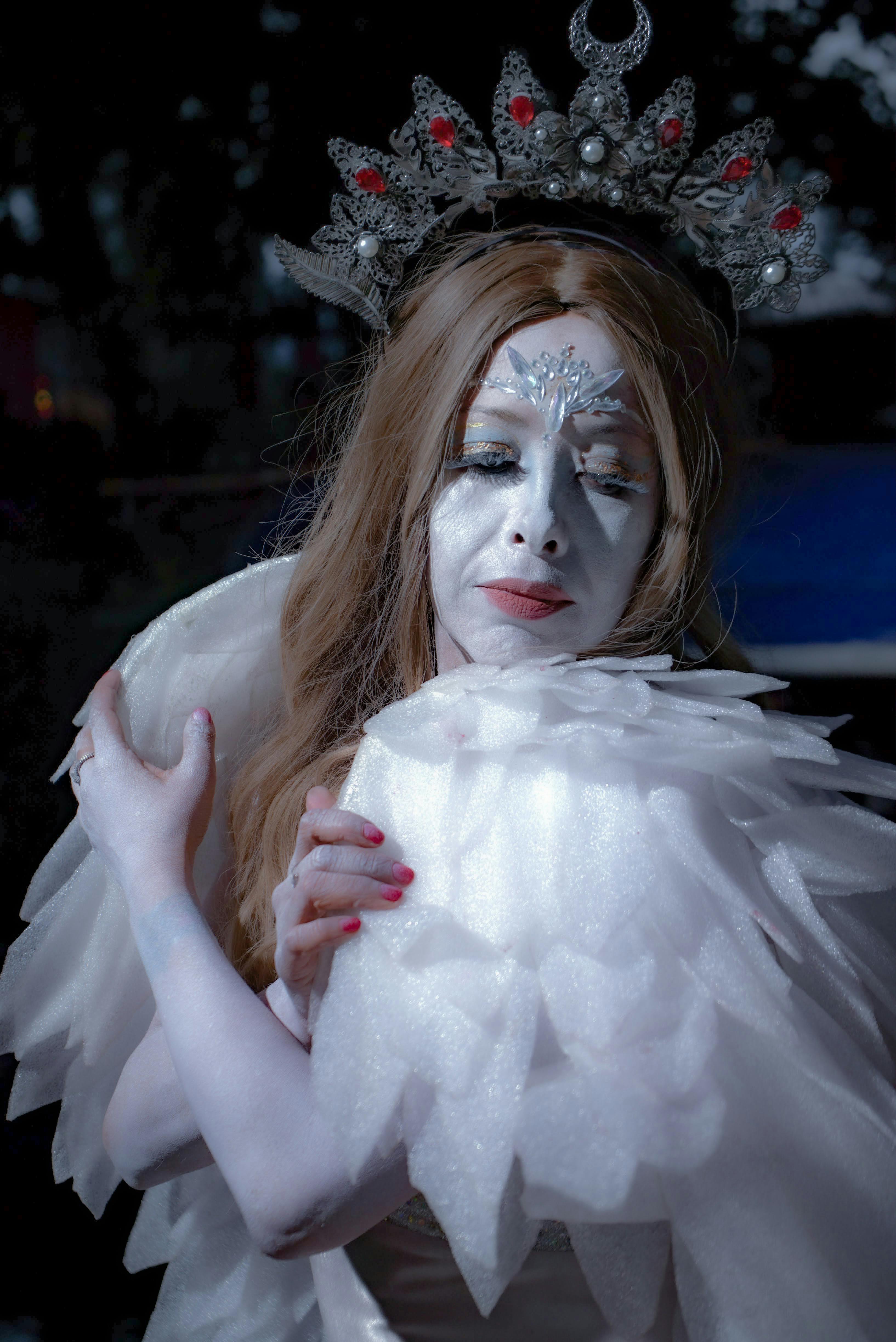 grátis Personagem de fantasia elegante com coroa e traje branco em luz cinematográfica. Foto profissional