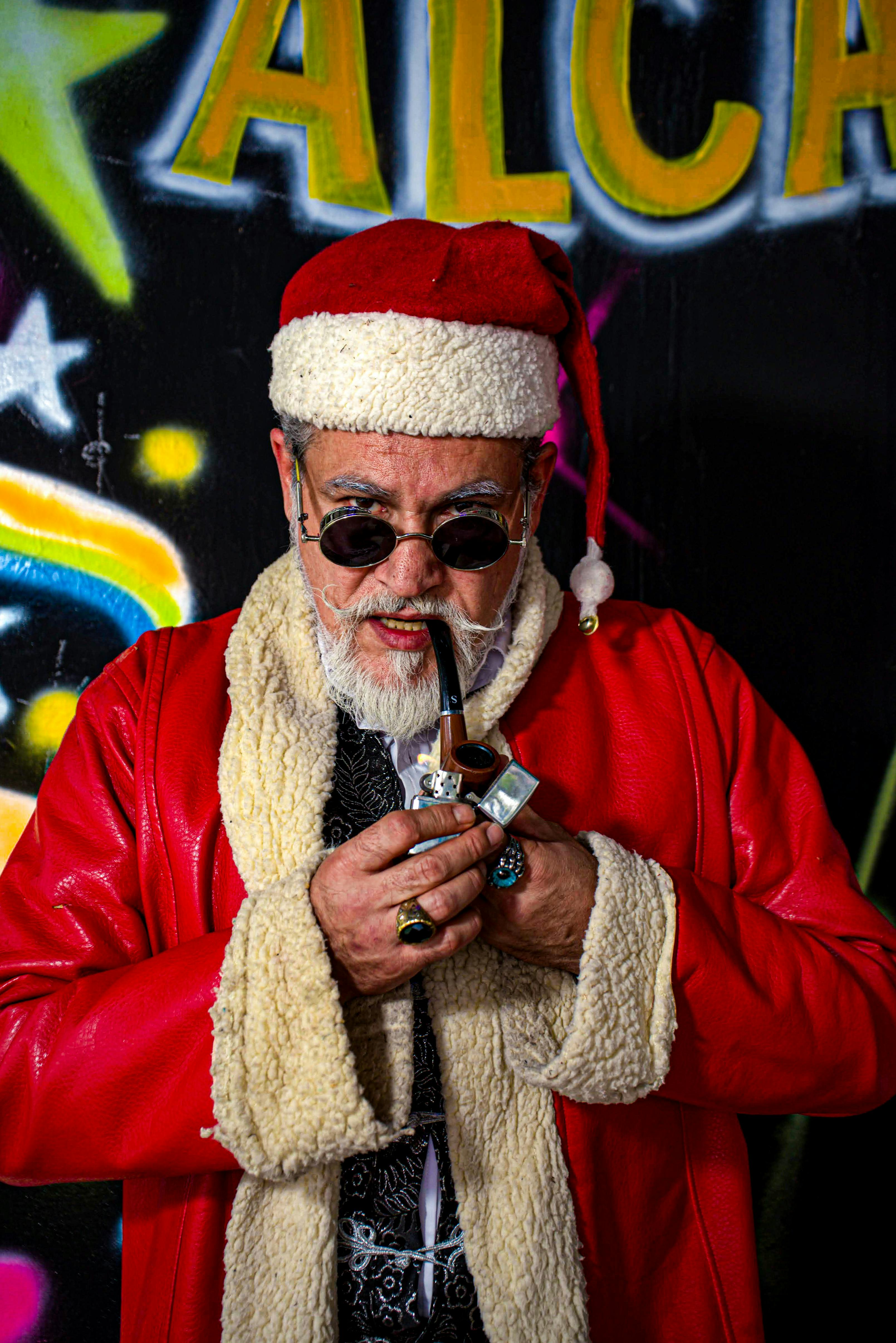 Cool Santa Claus in red coat with pipe against vibrant graffiti wall.