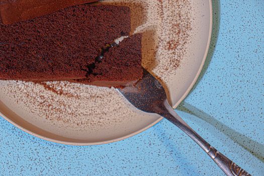 A delicious slice of chocolate cake with a fork on a speckled plate. Perfect for dessert lovers.
