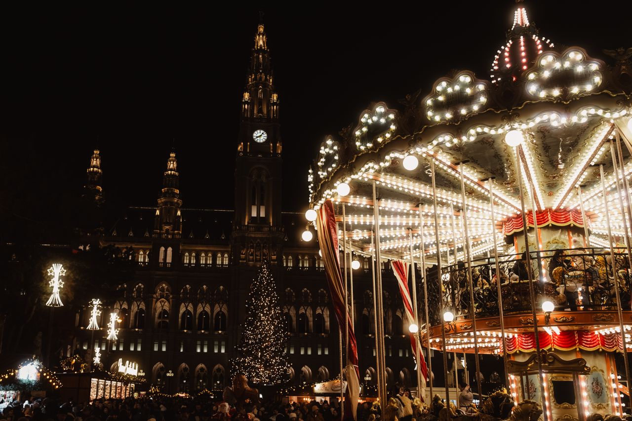 A vibrant night scene of a carousel at a Christmas market in Vienna, with festive lights and decorations creating a magical atmosphere.