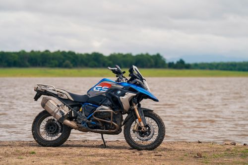 Free Blue adventure motorcycle parked by a scenic lakeside, ideal for travel and exploration themes. Stock Photo