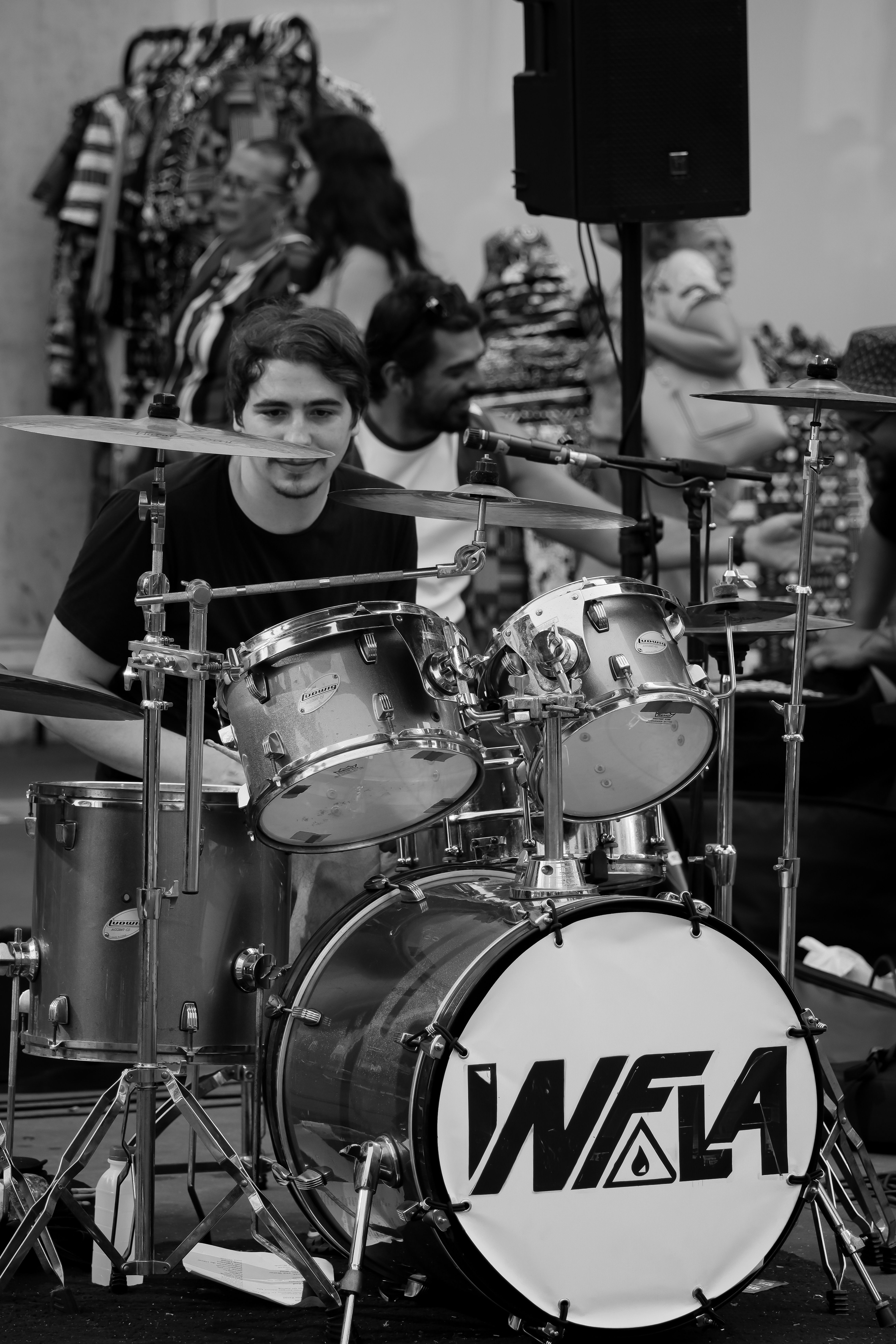 Black and white photo of a street drummer performing at an outdoor event.