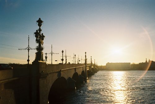 Free A picturesque view of a historic bridge at sunset with a calm river reflecting the warm light. Stock Photo