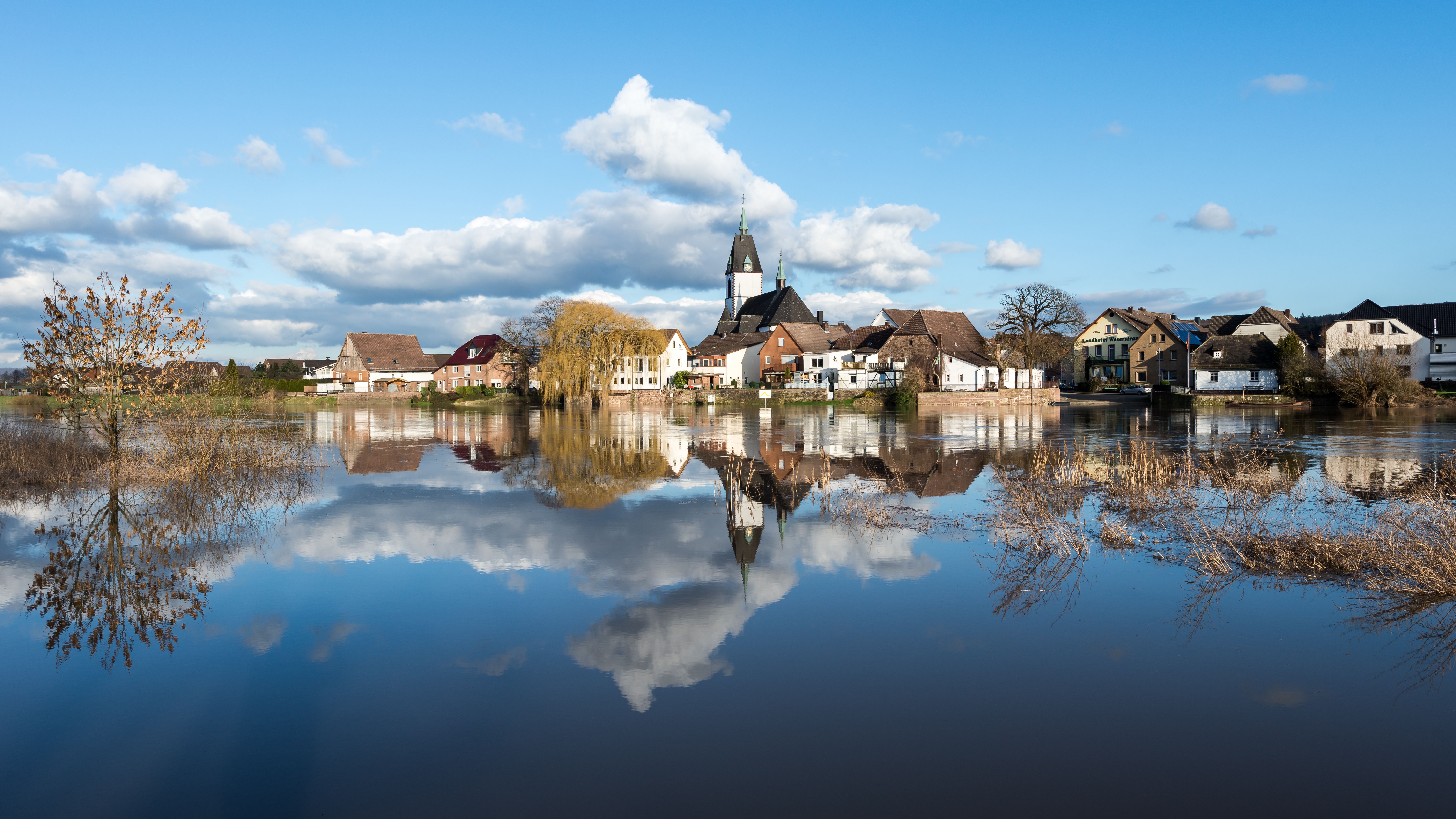Peaceful riverfront village in Höxter, Germany with beautiful reflections on a clear day.