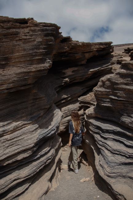 Woman navigating unique rock formations in Lanzarote, Spain on a clear day.
