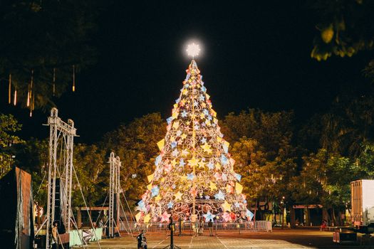 A vibrant, multi-colored Christmas tree shining brightly at night, symbolizing holiday cheer.