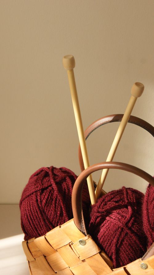 Free Warm knitting scene with wooden needles and red yarn in a rustic basket. Stock Photo