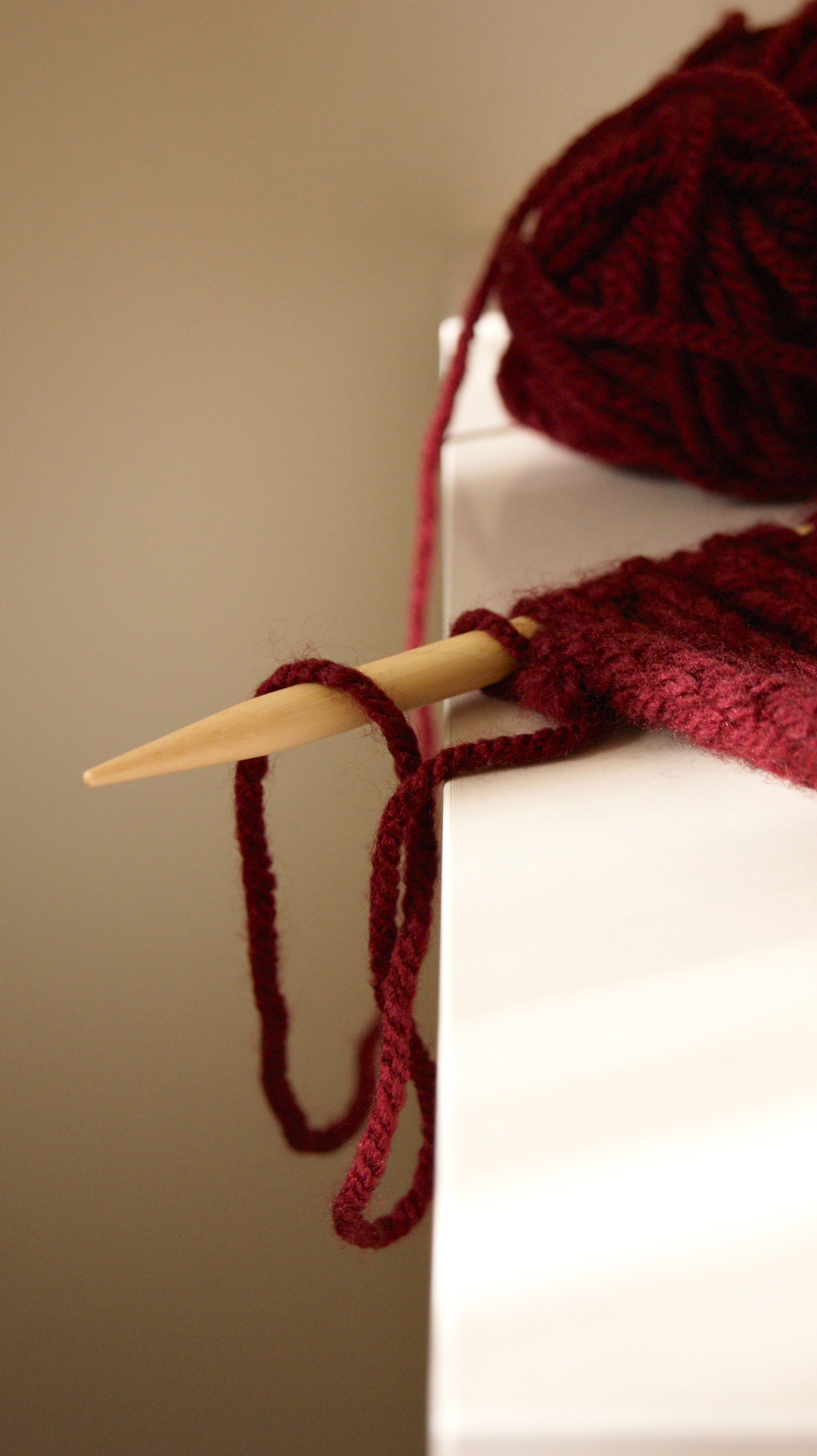 Burgundy yarn and knitting needles